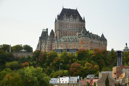 Photo de la ville de Québec avec le Château Frontenac surplombant la Basse-Ville et un boulevard où circulent des autos et un autobus.